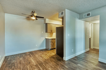 an empty living room and kitchen with a ceiling fan